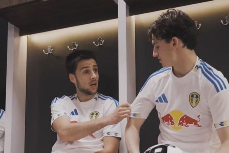 Ilia Gruev holds Brenden Aaronson's sleeve during an advert for Leeds United's new kit.