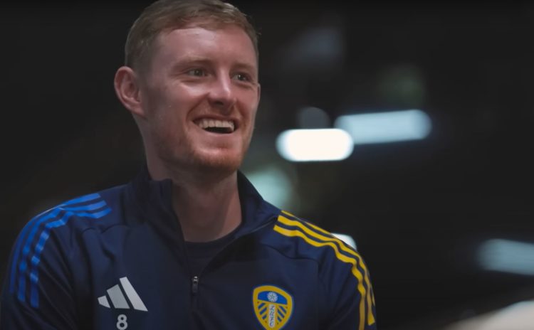Sean Longstaff smiles wearing a Leeds United tracksuit top.