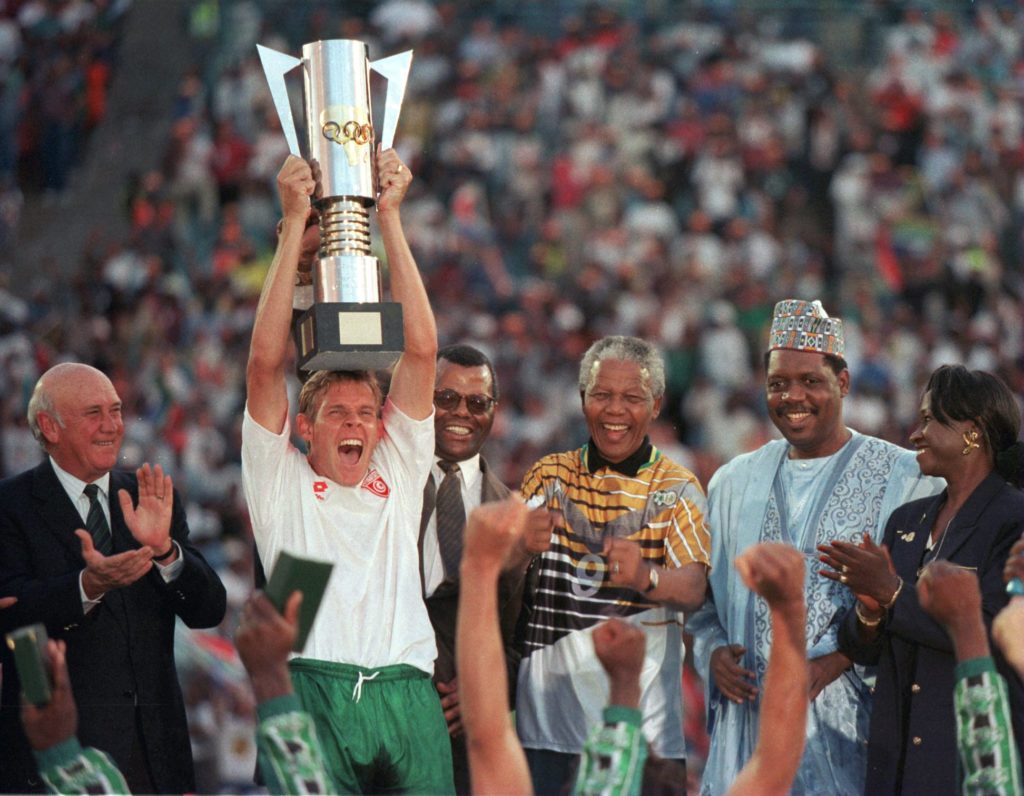 Neil Tovey lifts AFCON trophy next to Nelson Mandela.